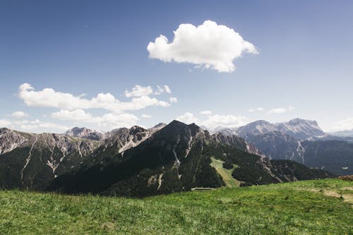 Green Grass Field Near Mountain Under Blue Sky