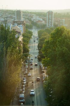 Aerial view capturing traffic in Madrid with trees lining the streets and buildings under a sunset glow.