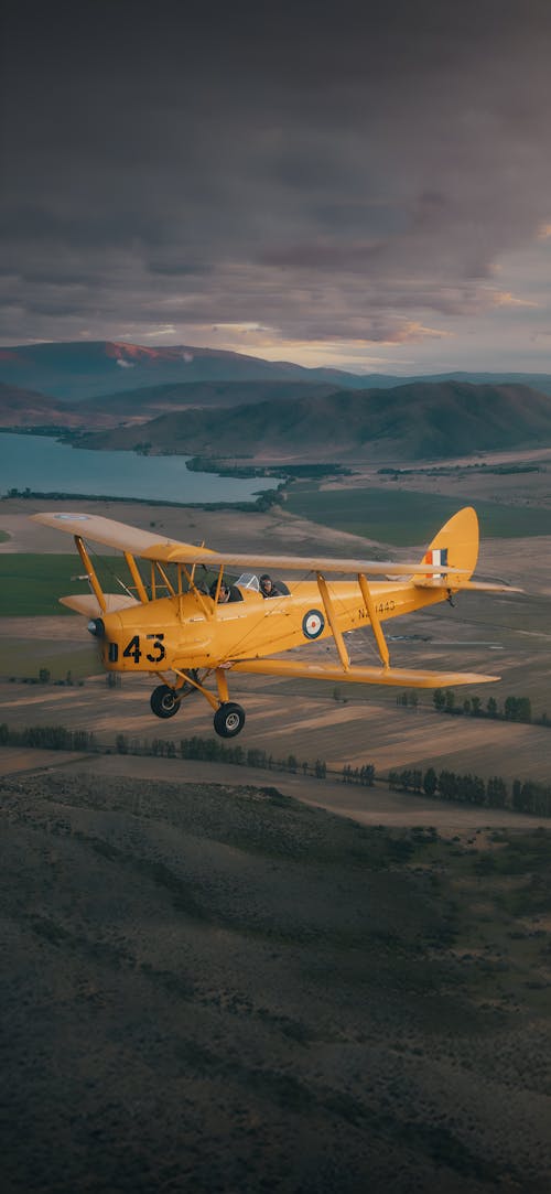 Yellow Biplane flying in the mountains of New Zealand wallpaper