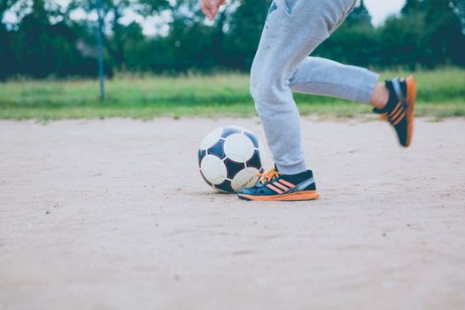 Young player practicing soccer on a sandy outdoor field, capturing motion and fun.