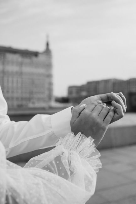Close-up of a couple holding hands in a romantic black and white wedding scene.