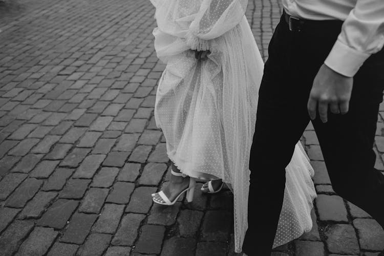 A Wedding Couple Standing On Pavement In Black And White