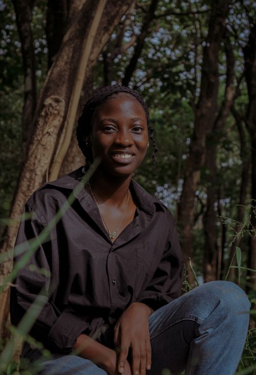 Free A woman in a black shirt posing in a lush Nigerian forest, exuding elegance and serenity. Stock Photo