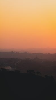 Stunning sunset view over rolling hills with vibrant orange gradient sky.