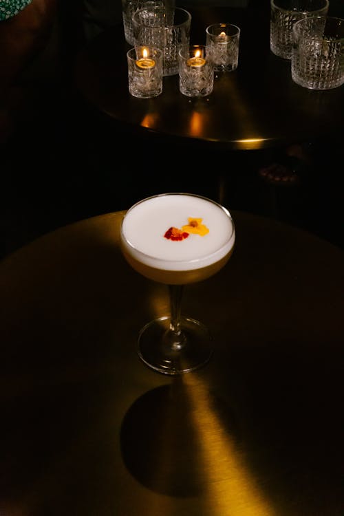 Glass of Cocktail on a Shiny Metal Table in a Dim Lit Bar