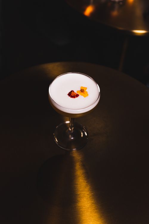 Free Stylish cocktail with floral garnish on a shiny table, perfect for upscale nightlife settings. Stock Photo
