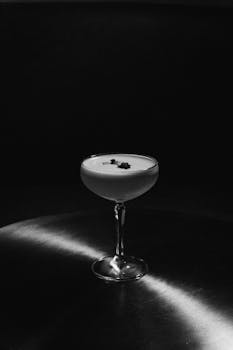 A sophisticated black and white image of a cocktail glass on a reflective surface, ideal for elegant settings.
