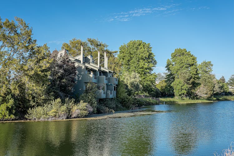 House With Trees Around On Riverbank