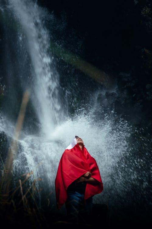 Man with Polish Flag Standing Under Waterfall