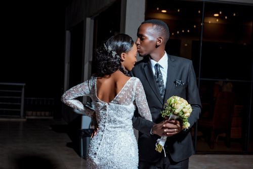 Free Stylish newlyweds in elegant attire share an intimate moment with a kiss under the night sky. Stock Photo