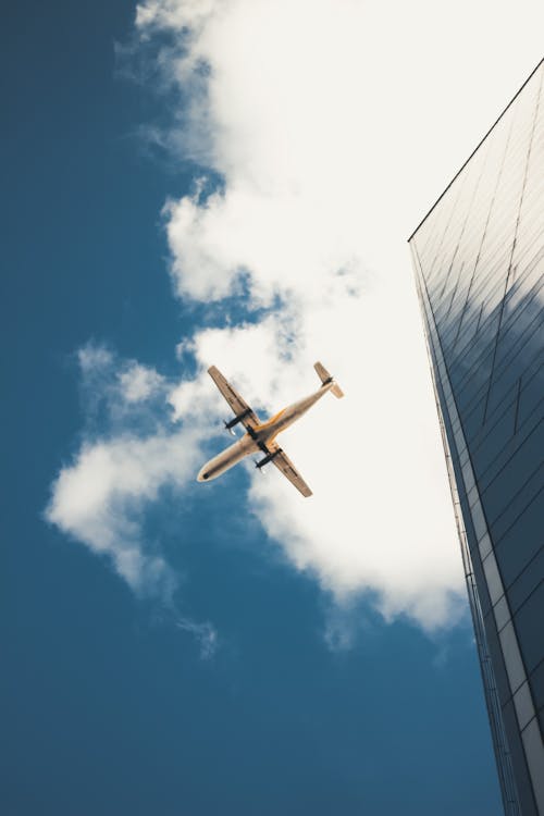 Airplane Flying over Building in City