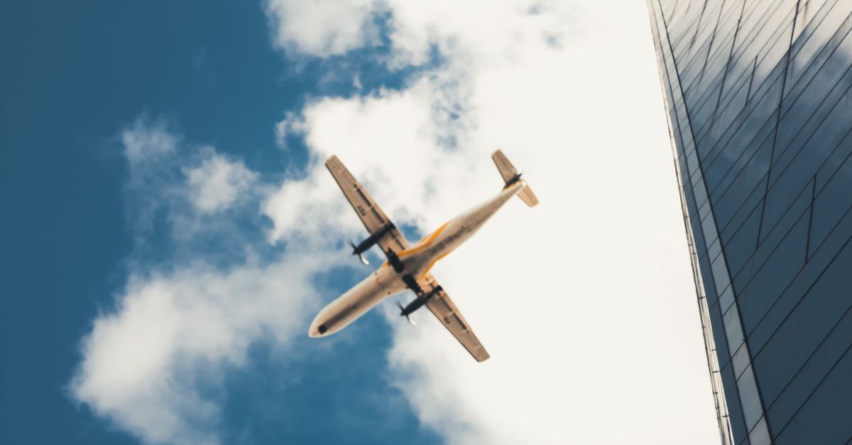 Airplane Flying over Building in City · Free Stock Photo