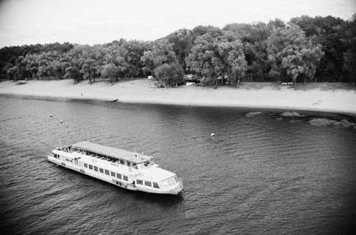 Free Black and white aerial photo of a passenger ship sailing along a riverbank with trees. Stock Photo