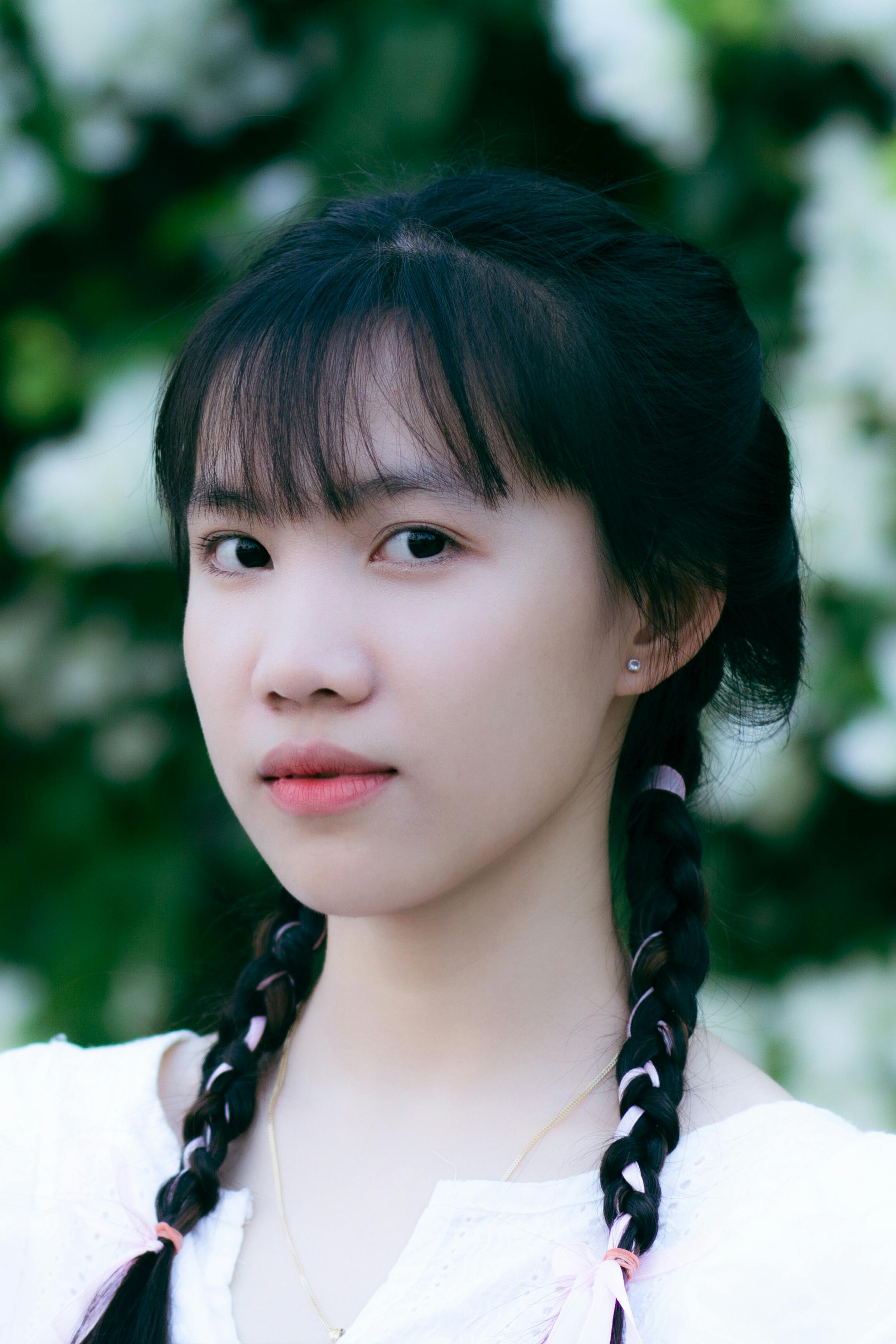 Close-up portrait of a woman with braided hair, captured outdoors in natural light.