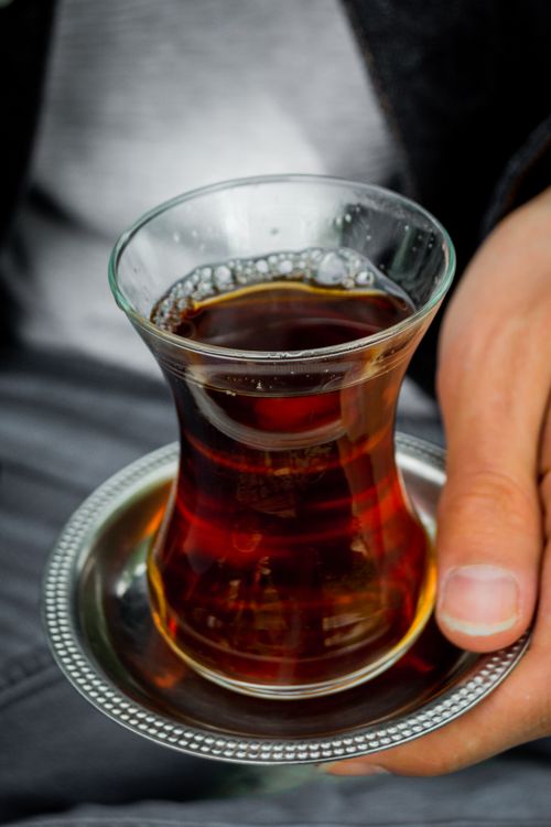 Free A person holding Turkish tea in a clear glass with a silver plate. Perfect for lifestyle and culinary themes. Stock Photo