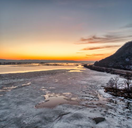 Free Breathtaking view of Minneiska, Minnesota's icy shoreline during a vibrant winter sunset. Stock Photo