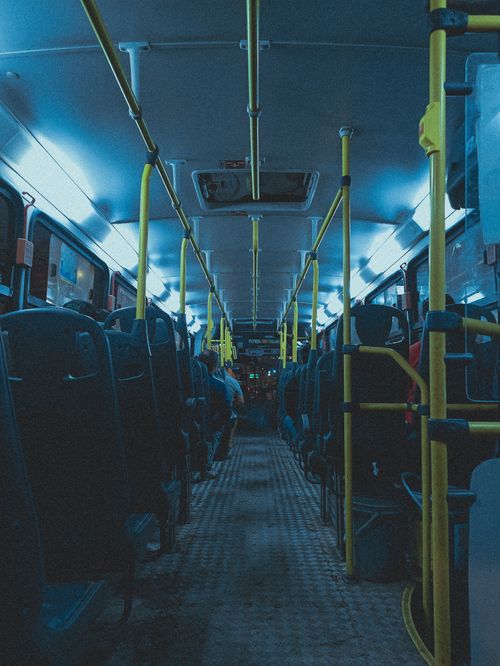 Free Dimly lit bus interior at night with empty seats and neon lights, capturing urban commuting ambiance. Stock Photo