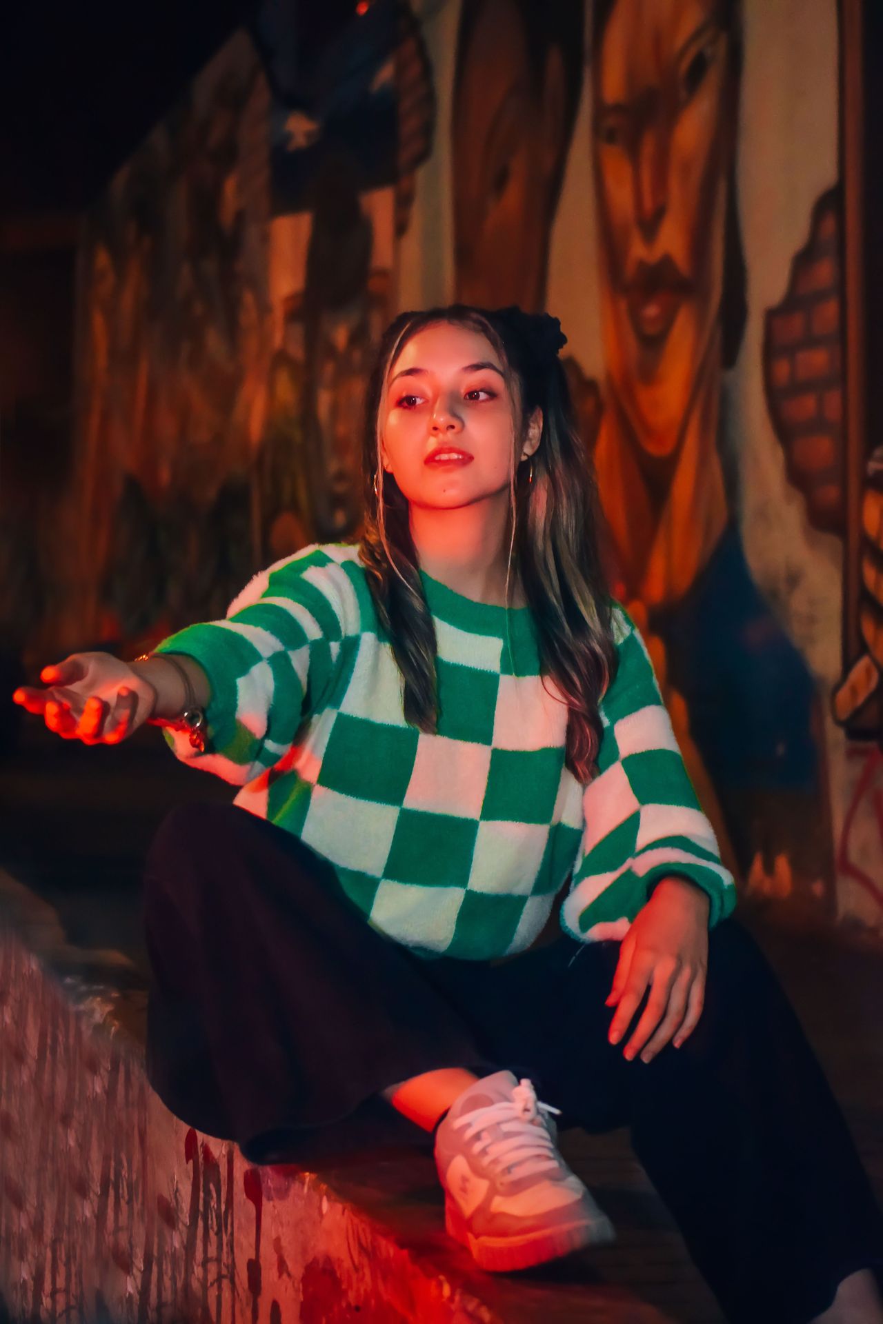 Woman in an oversized green and white checkerboard sweater with black pants and sneakers