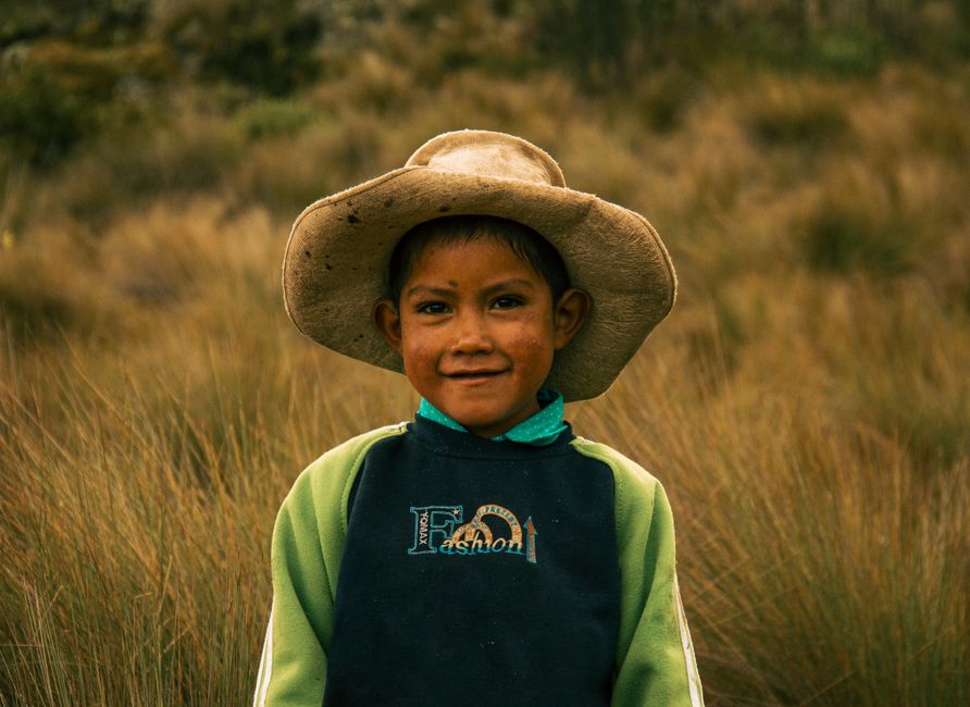 Portrait of a young boy smiling in a rustic field in Cajamarca, Perú, showcasing rural childhood.