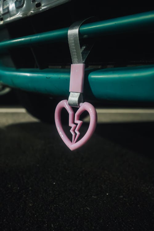 Free Pink Broken Heart Tsurikawa Ring Attached to a Green Car Bumper Stock Photo