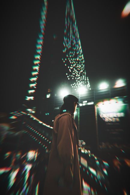 Blurry cityscape at night with light trails and a lone figure adding mystery and intrigue.