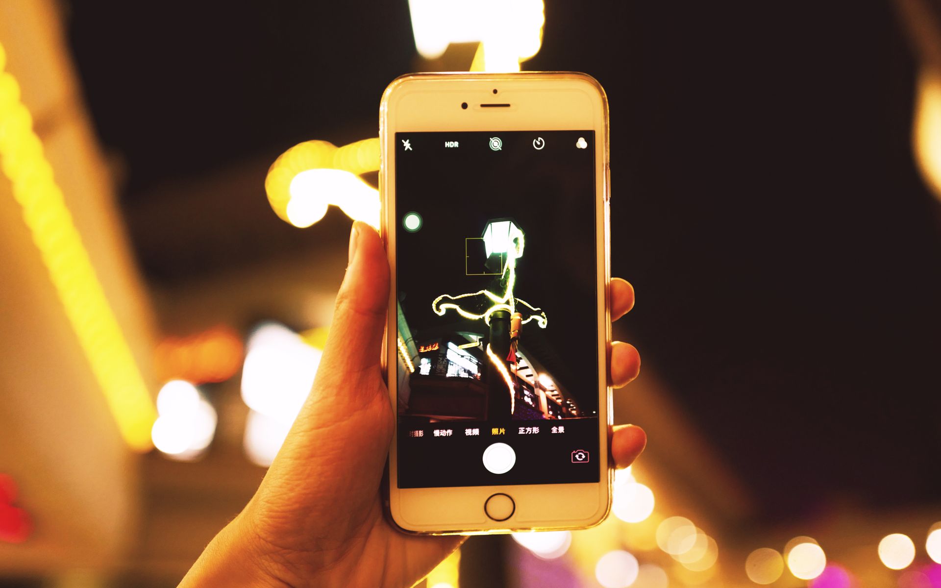 Hand holding smartphone capturing city lights at night. Perfect for urban and tech themes.