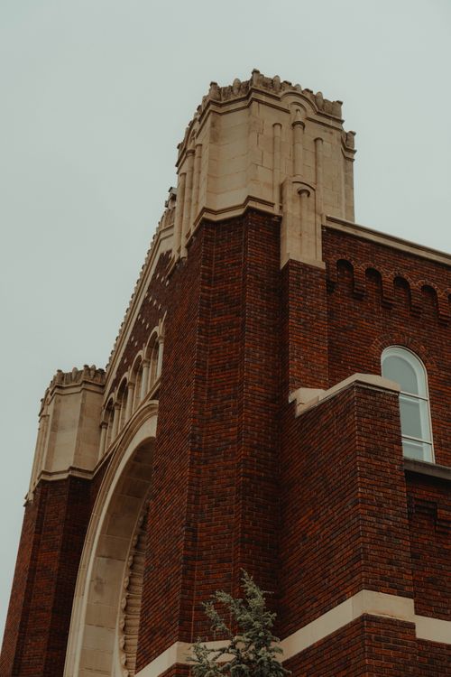 Free Impressive low-angle view of a red brick cathedral tower highlighting Gothic architectural details. Stock Photo