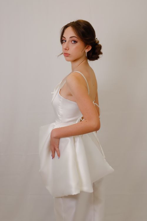 Free Stylish woman posing in a white dress against a neutral backdrop. Stock Photo
