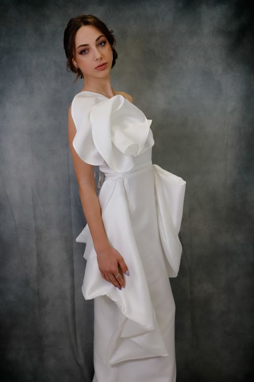 Free Studio portrait of a woman in a stylish white evening gown against a gray background. Stock Photo