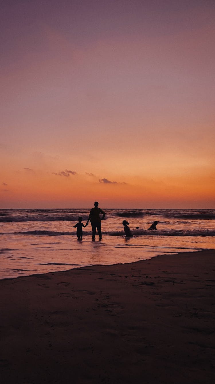 Parent And Children On Sea Shore At Sunset