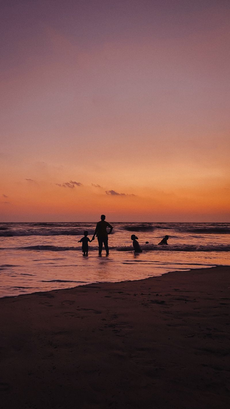 A parent and children walking together at sunset