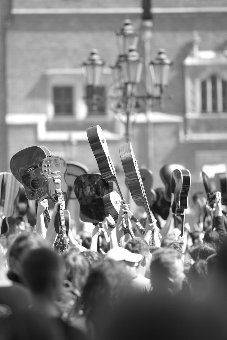 A Black And White Photo Of A Crowd Of People Holding Guitars