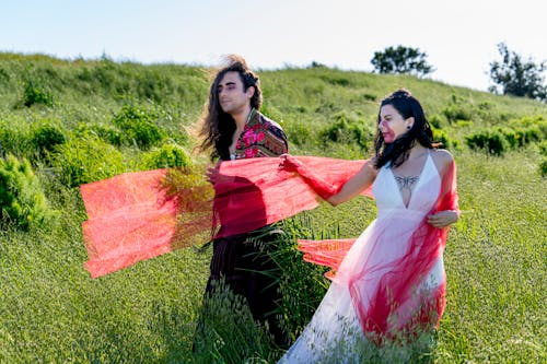 Man with Long Hair and Woman Standing on a Meadow 