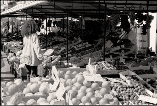 A bustling street market with fruits and vegetables. Captured in black and white.