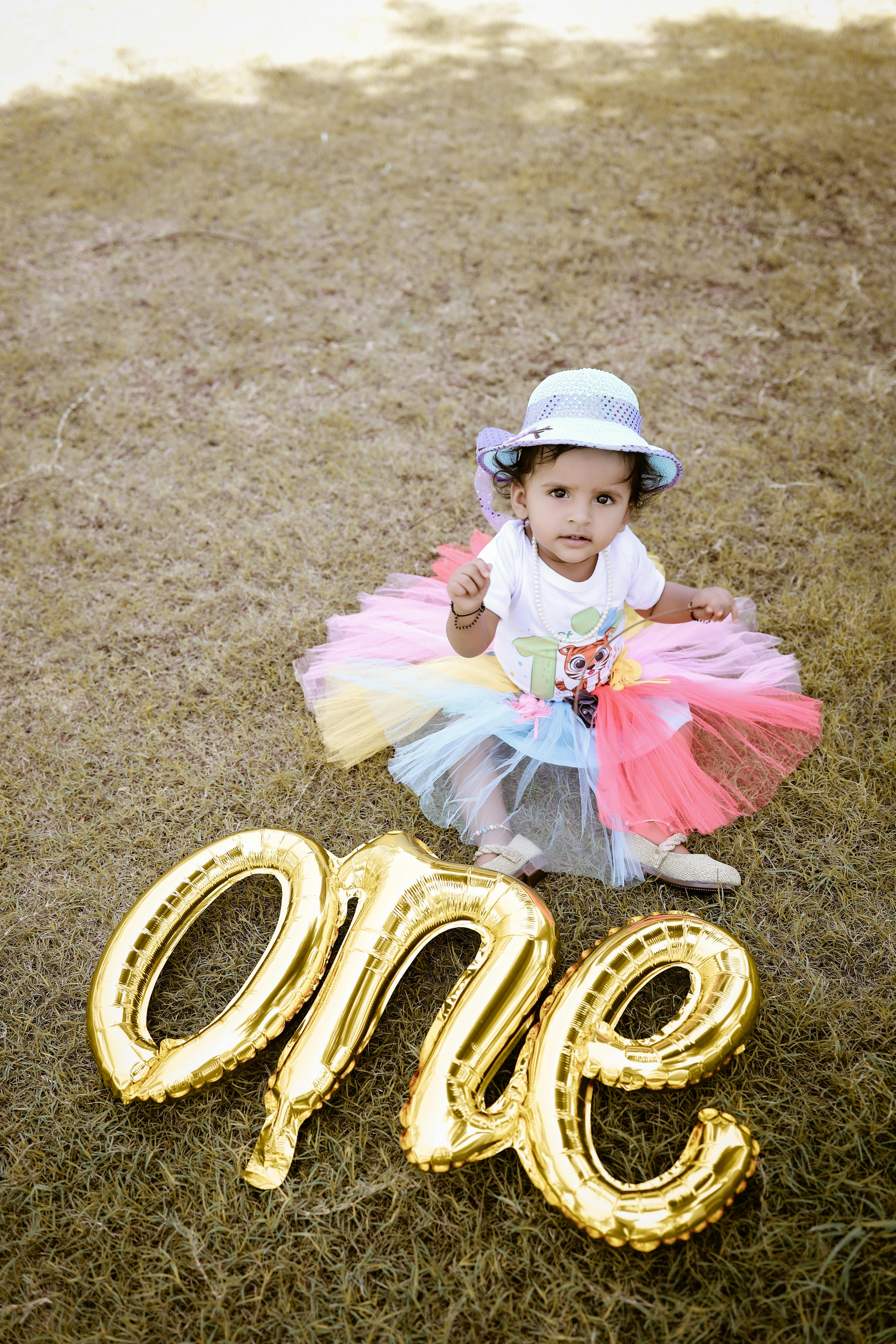 Cute baby girl in colorful tutu celebrating her first birthday outdoors.