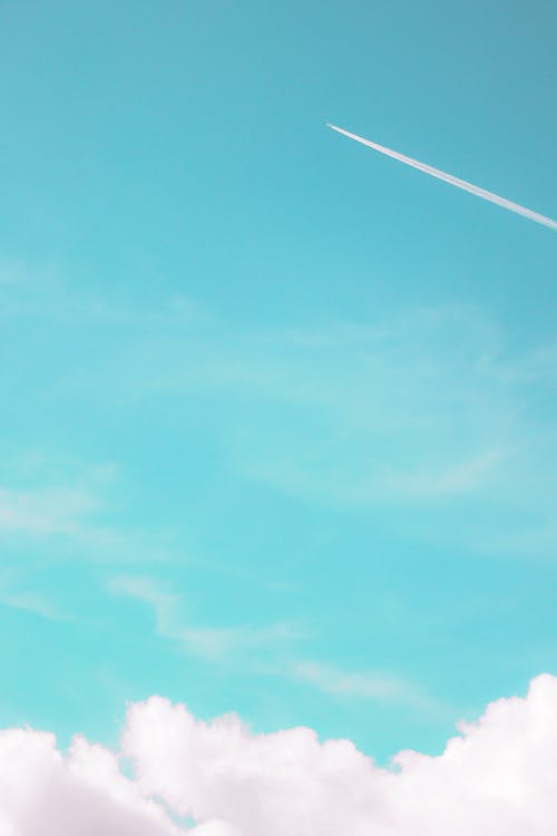 An Airplane High up against a Blue Sky 