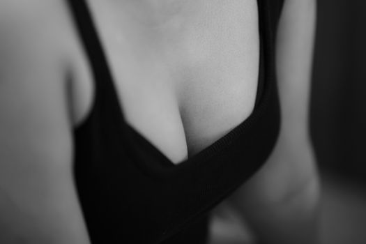 Black and white close-up of a woman's torso in a tank top, showcasing skin texture.