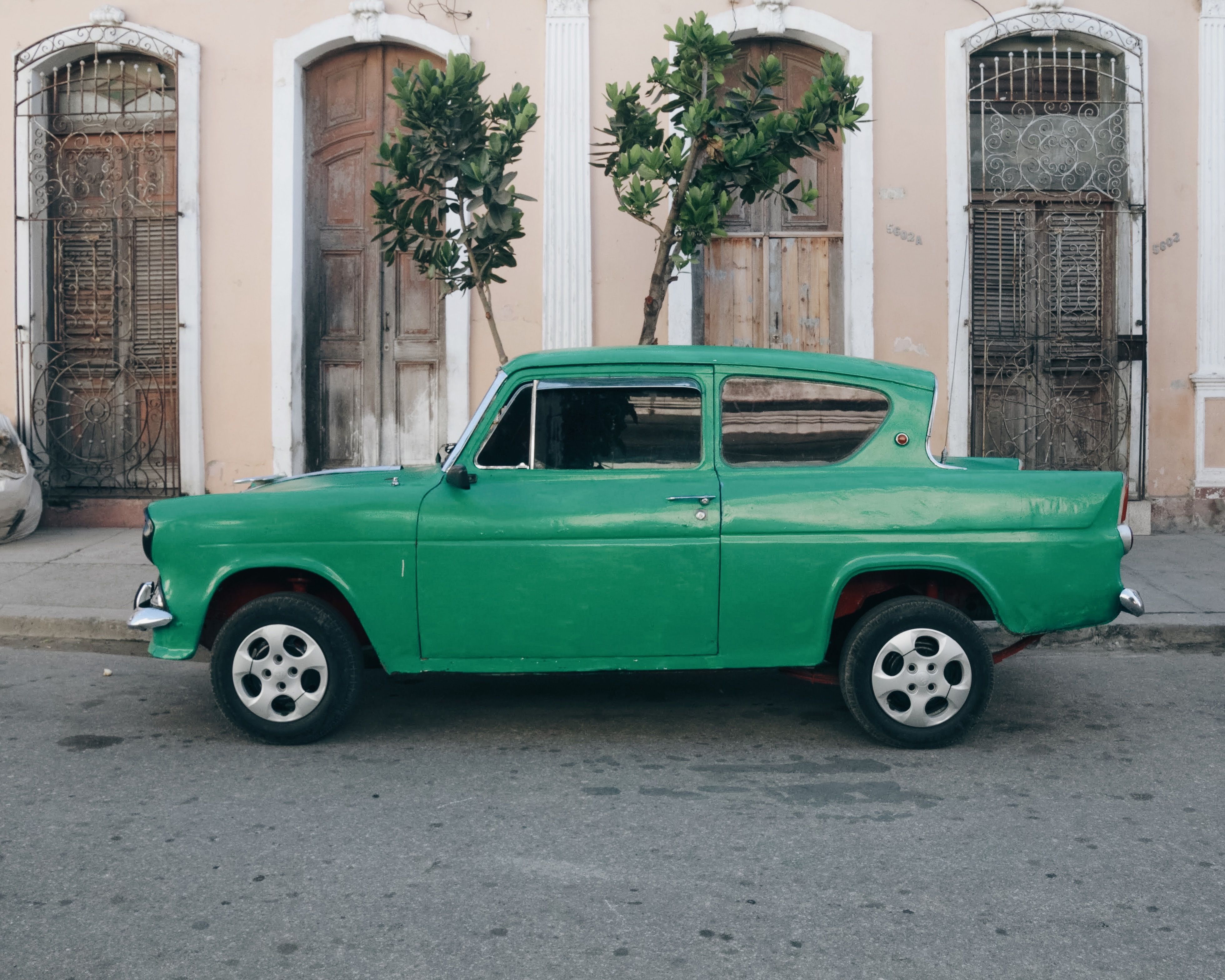Classic green car parked by pastel buildings