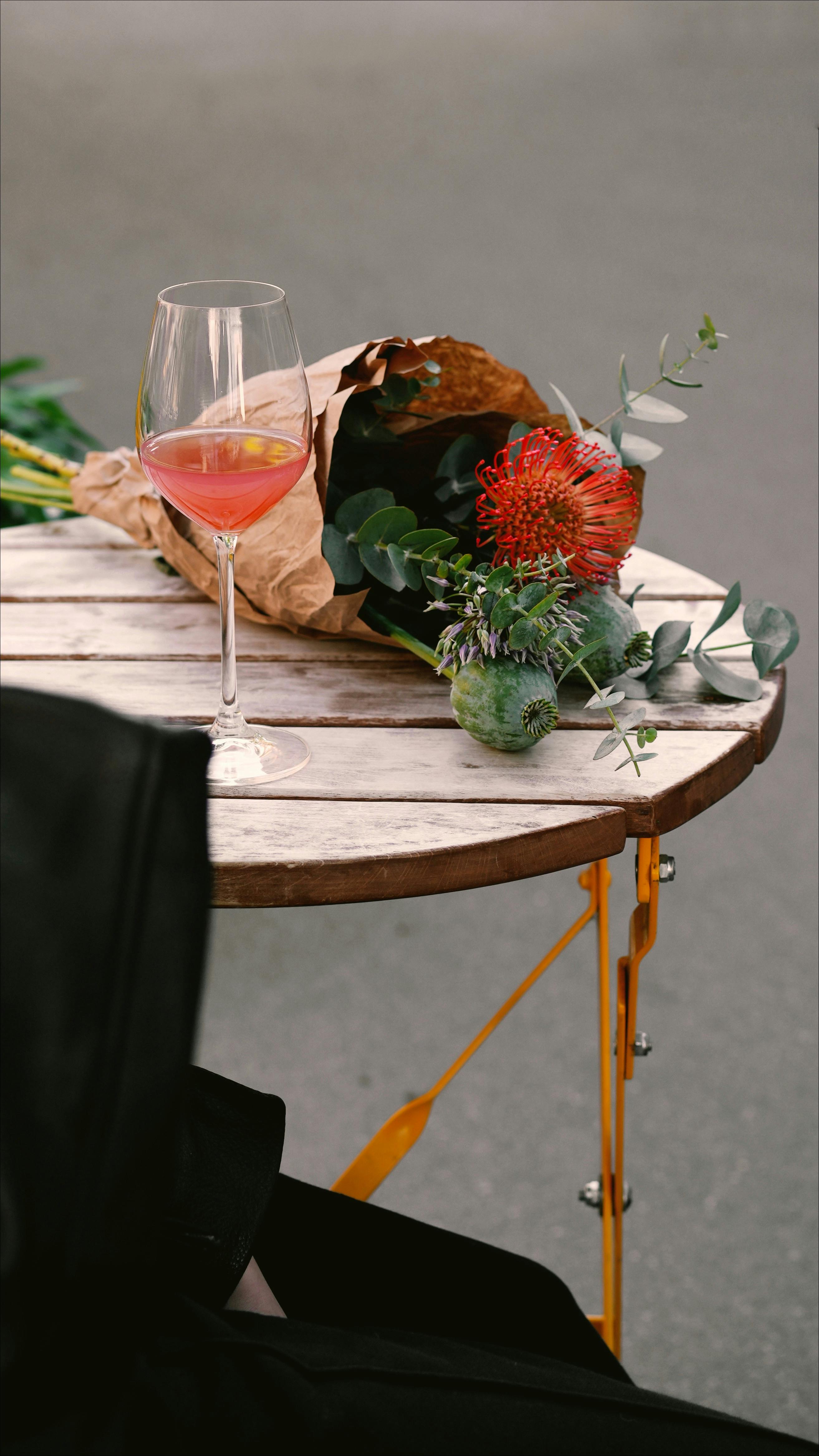 A stylish café setting with exotic flowers and a wineglass on a rustic table.