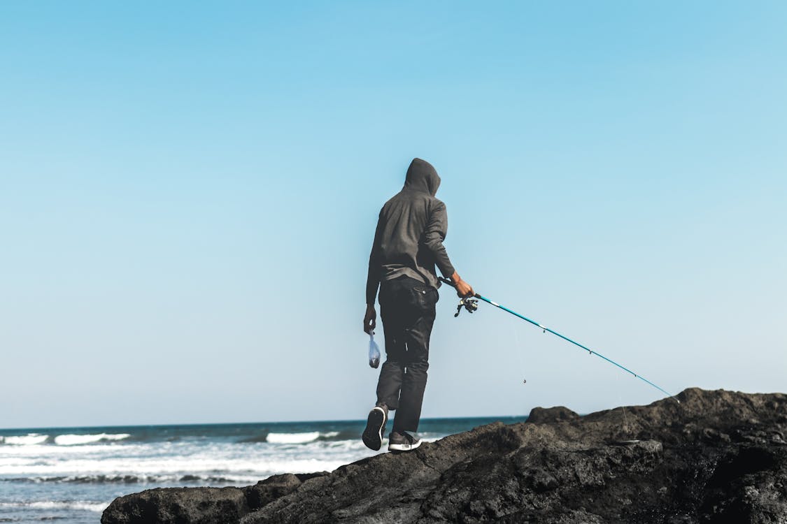 Free Person Fishing on Seashore Stock Photo