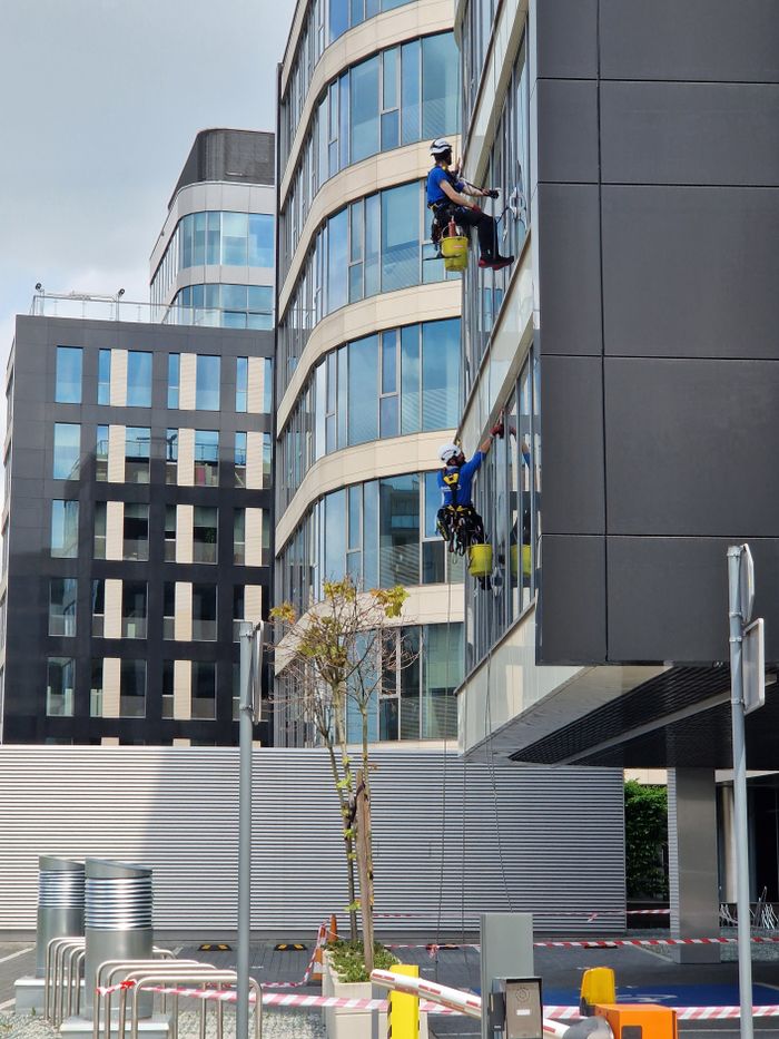 Two workers cleaning windows on a modern office building