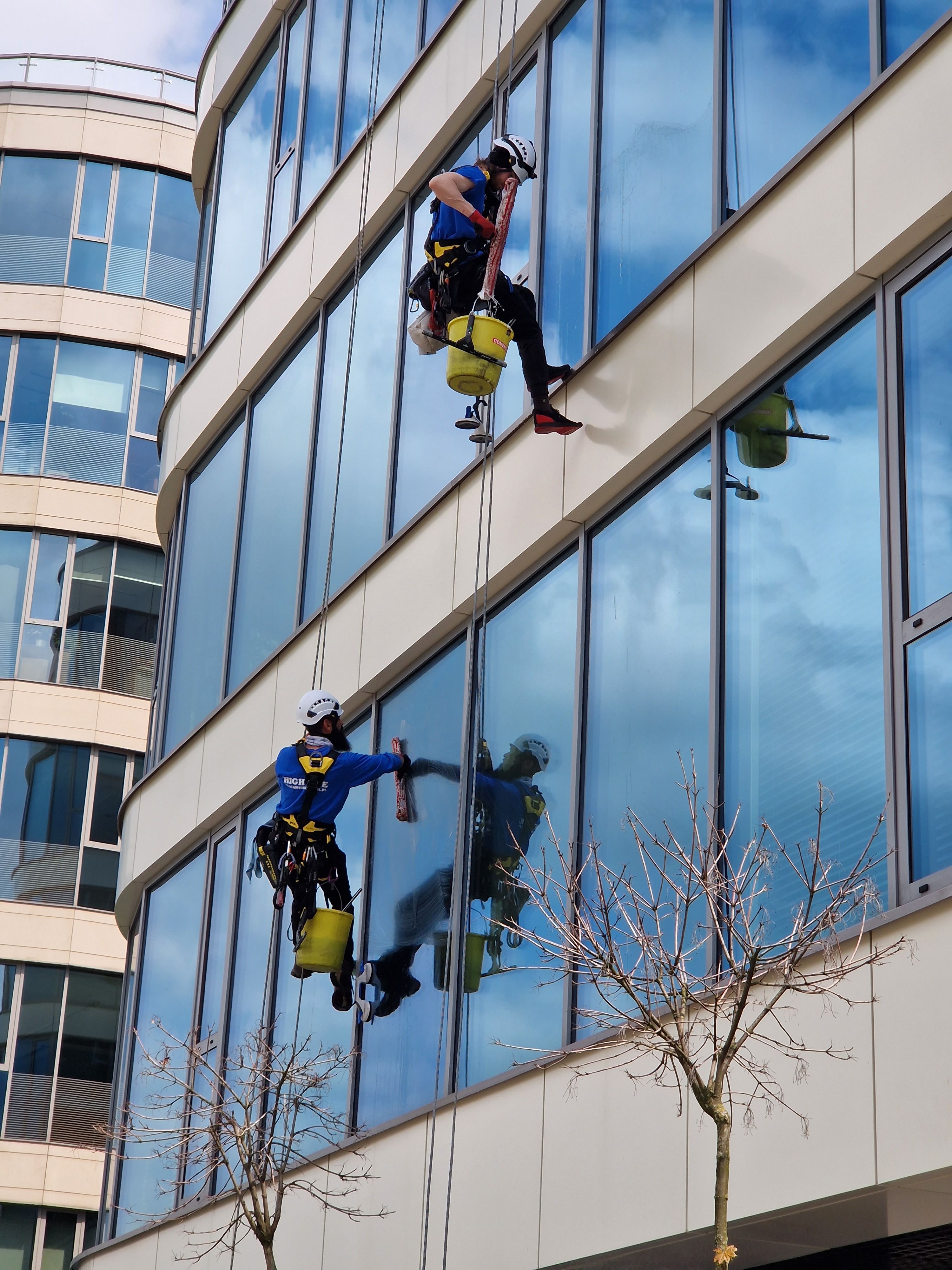 Deux professionnels nettoyant les vitres en hauteur d'un immeuble