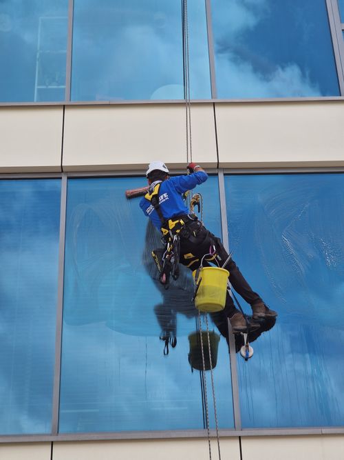 Free Worker cleaning skyscraper windows with safety gear and equipment. Stock Photo