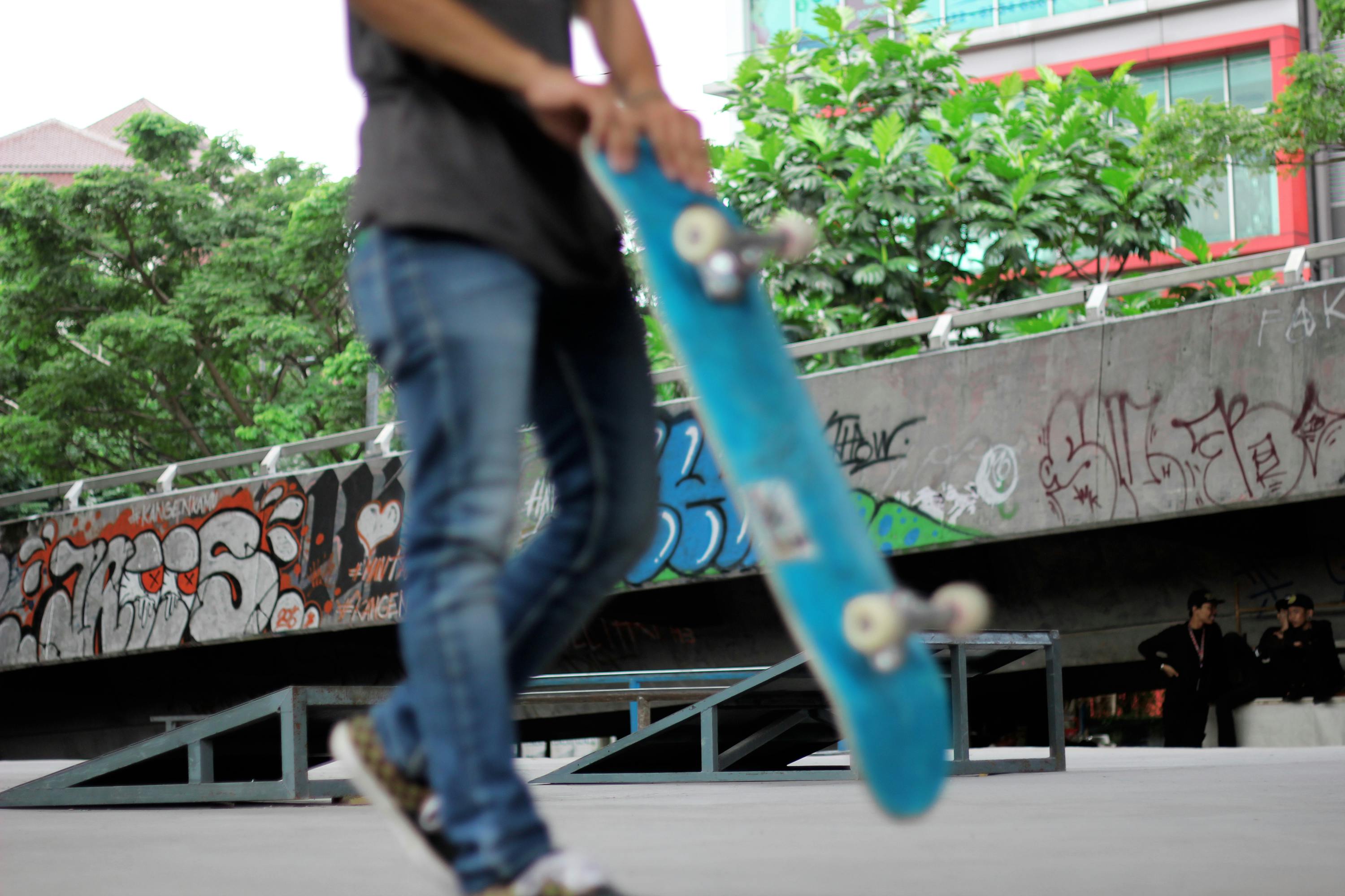 man holding teal skateboard