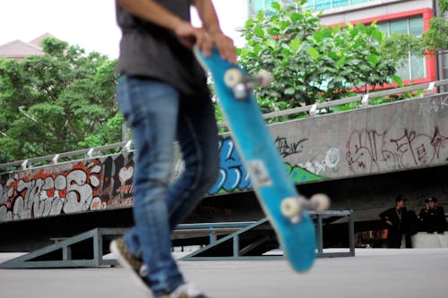 Man Holding Teal Skateboard