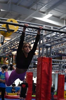 Focused woman practicing hanging obstacles course in an indoor gym environment.
