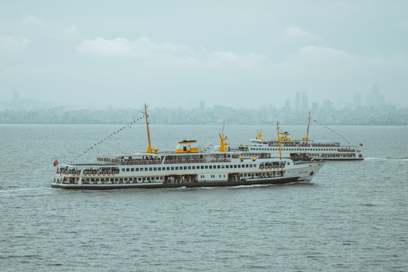 Istanbul ferries cruising on the Bosphorus with the city skyline in the background on an overcast day.