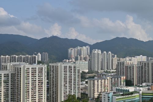 Free A wide view of Hong Kong's urban landscape featuring skyscrapers against a mountain backdrop. Stock Photo