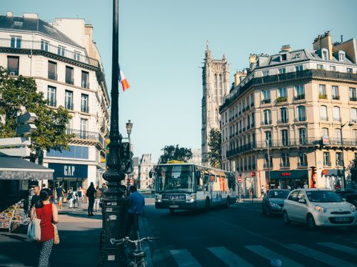 Free A lively Paris street scene showcasing historic architecture, vehicles, and pedestrians. Stock Photo