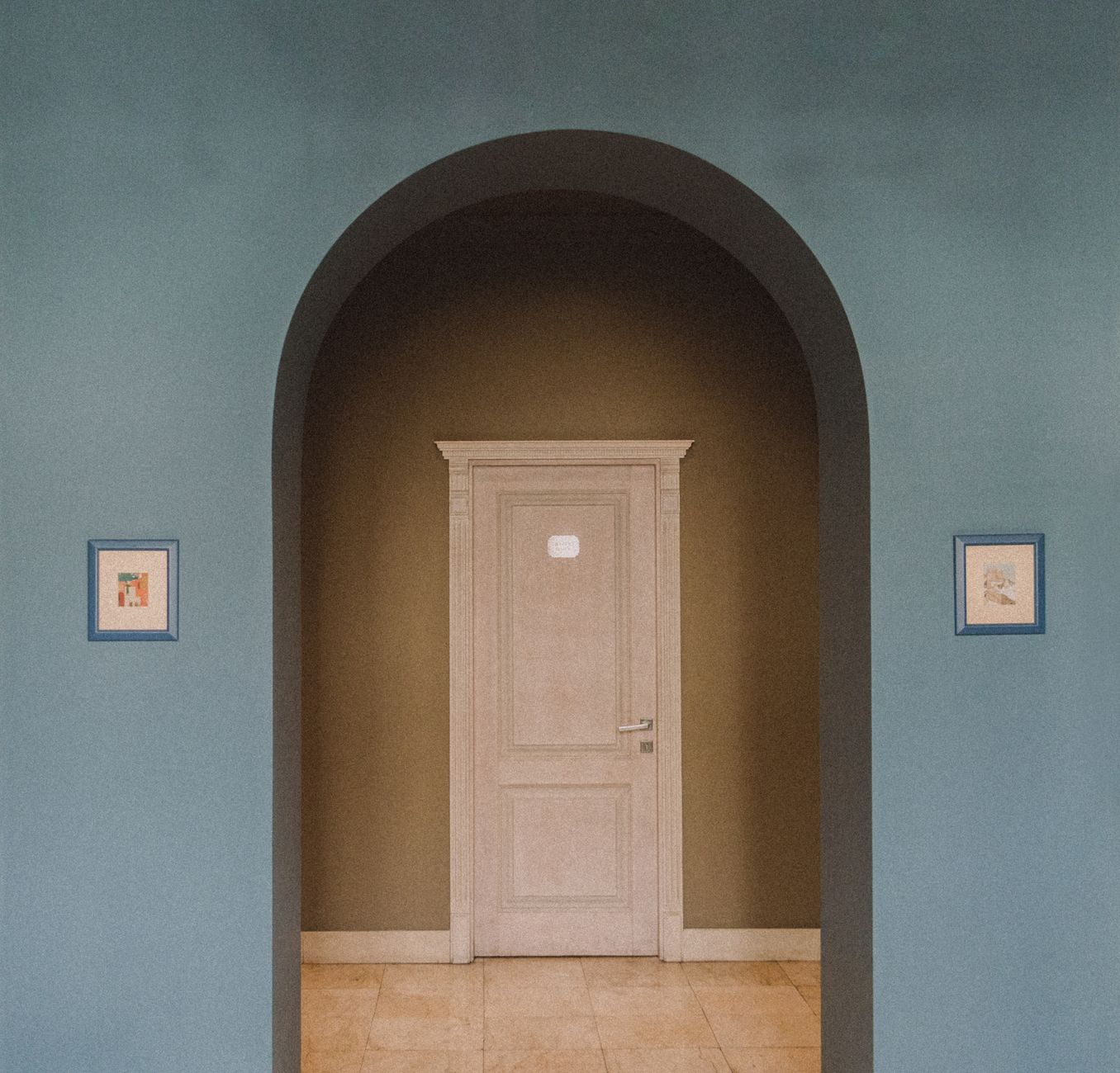 Interior focus on an archway leading to a classic door, flanked by framed artwork.